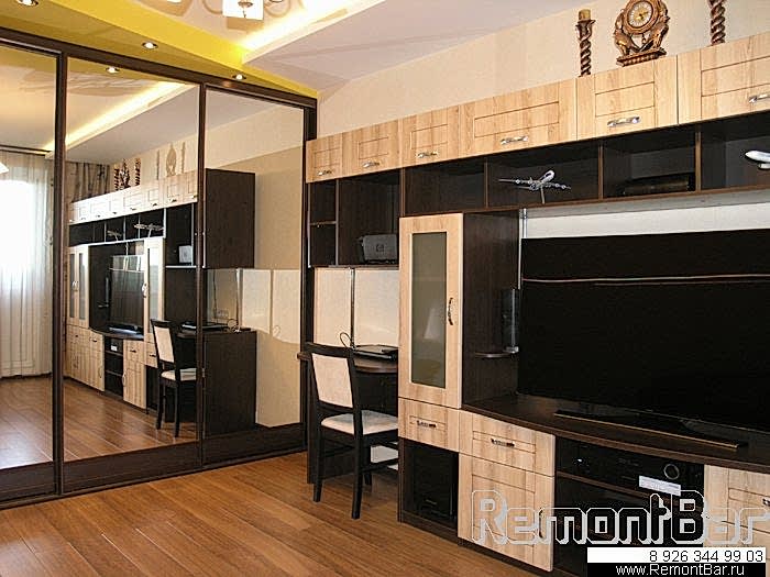 Вся мебель в гостиной выполнена по спецзаказу на фабрике наших партнеров и по эскизу самого заказчика. Вообще, в итоговом варианте заказчиком допущено достаточно много отступлений от проекта. В частности, в последний момент, подобранную для гостиной мебель заменили на придуманную им корпусную стенку, в которой объединены и рабочий письменный стол, и тумбы, и полки (очень удобно получилось)