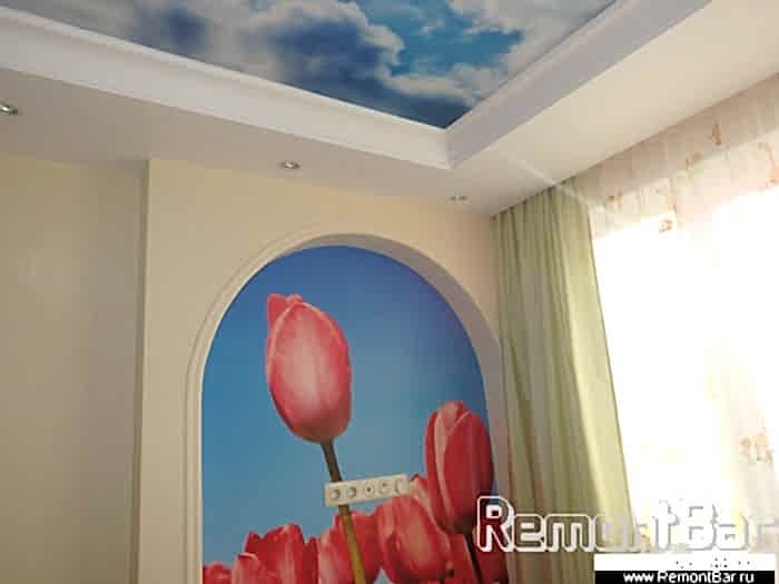 Потолок в детской комнате двухуровневый гипсокартонный с шумоизоляционным слоем. Основная центральная часть - фотообои, подобранные дизайнером, так же как и в арочной нише.