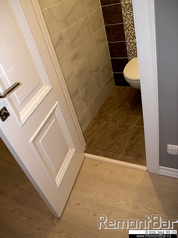 Порожек сделан из плитки в форме ступеньки с отделкой наружнего пластиковой раскладкой. Он обеспечивает небольшую разноуровневость полов (пол в санузле ниже, чем по квартире). Однако, под дверным полотном дополнительно установлен накладной (гибкий полиуретановый со скрытым крепежом) порожек, поскольку пол в коридоре - ламинат и по-другому стыковать его с плиткой невозможно